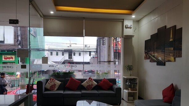 A modern living room with a glass coffee table, a sofa with red cushions, and a grey armchair. - Cherry Midtown Hotel (Olongapo)