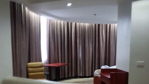 A living room with a beige sofa, a yellow armchair, a red table, and a red shelving unit. - Cherry Midtown Hotel (Olongapo)