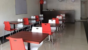A conference room with tables and chairs, a whiteboard, and a kitchenette area. - Cherry Midtown Hotel (Olongapo)