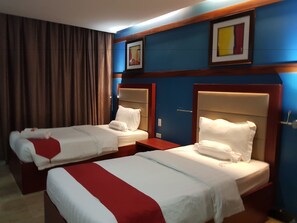 A hotel room with two beds, each with a headboard, a red and white striped bedspread, and a white pillow. There is a brown curtain on the window, and a framed picture on the wall. - Cherry Midtown Hotel (Olongapo)