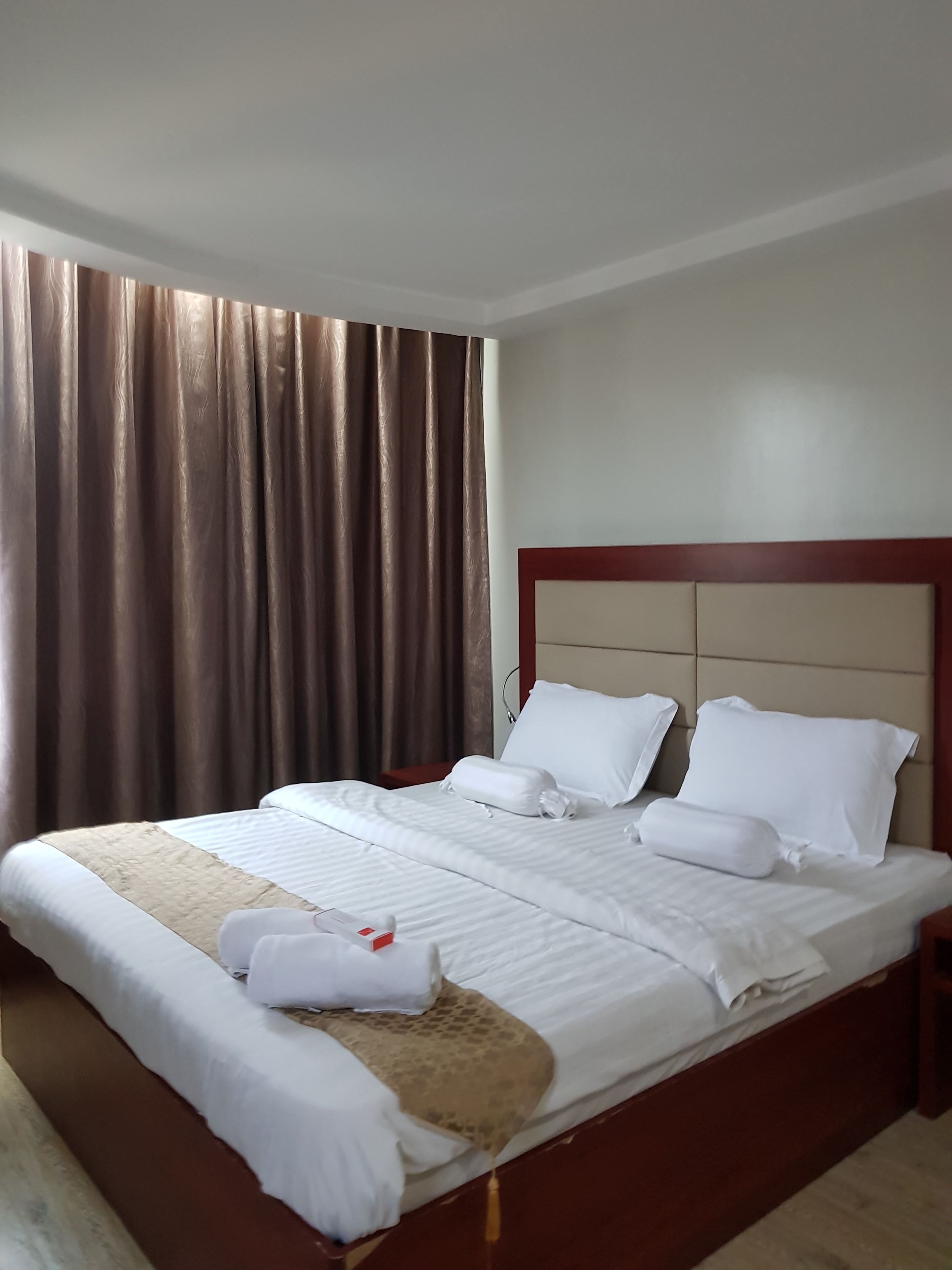 Habitación de hotel con una cama grande, dos almohadas, una manta y una toalla sobre la cama.