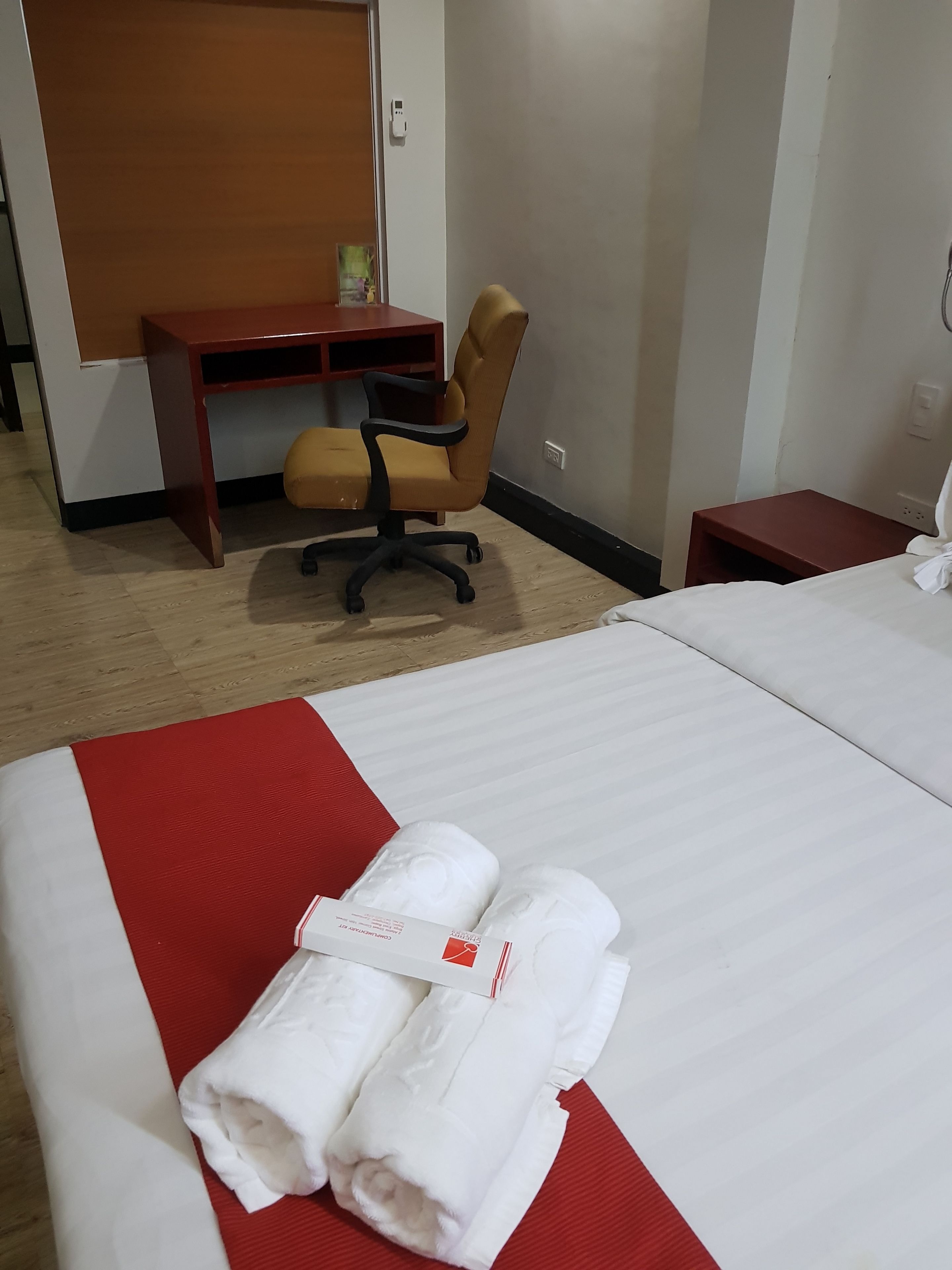 Una habitación de hotel con cama, escritorio, silla y mesita de noche.