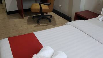 Una habitación de hotel con cama, escritorio, silla y mesita de noche.
