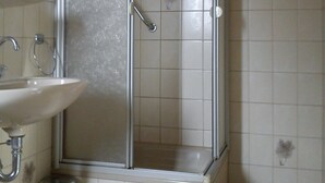 A bathroom with a shower enclosure, a sink, and a trash bin. - Hotel Rose (Ebersbach an der Fils)