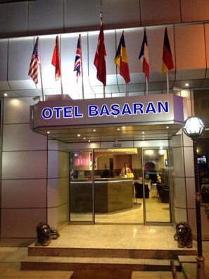 The entrance of the hotel with the name 'OTEL BASARAN' and multiple flags hanging above the entrance. - Grand Hotel Basaran (Bilecik)