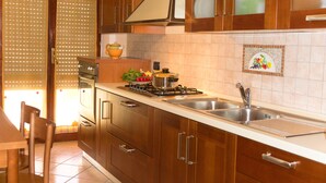 Una cocina con armarios de madera, estufa a gas, lavamanos y salpicadero de azulejos.