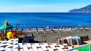 Una playa con sombrillas, sillas de descanso y una zona de juegos.