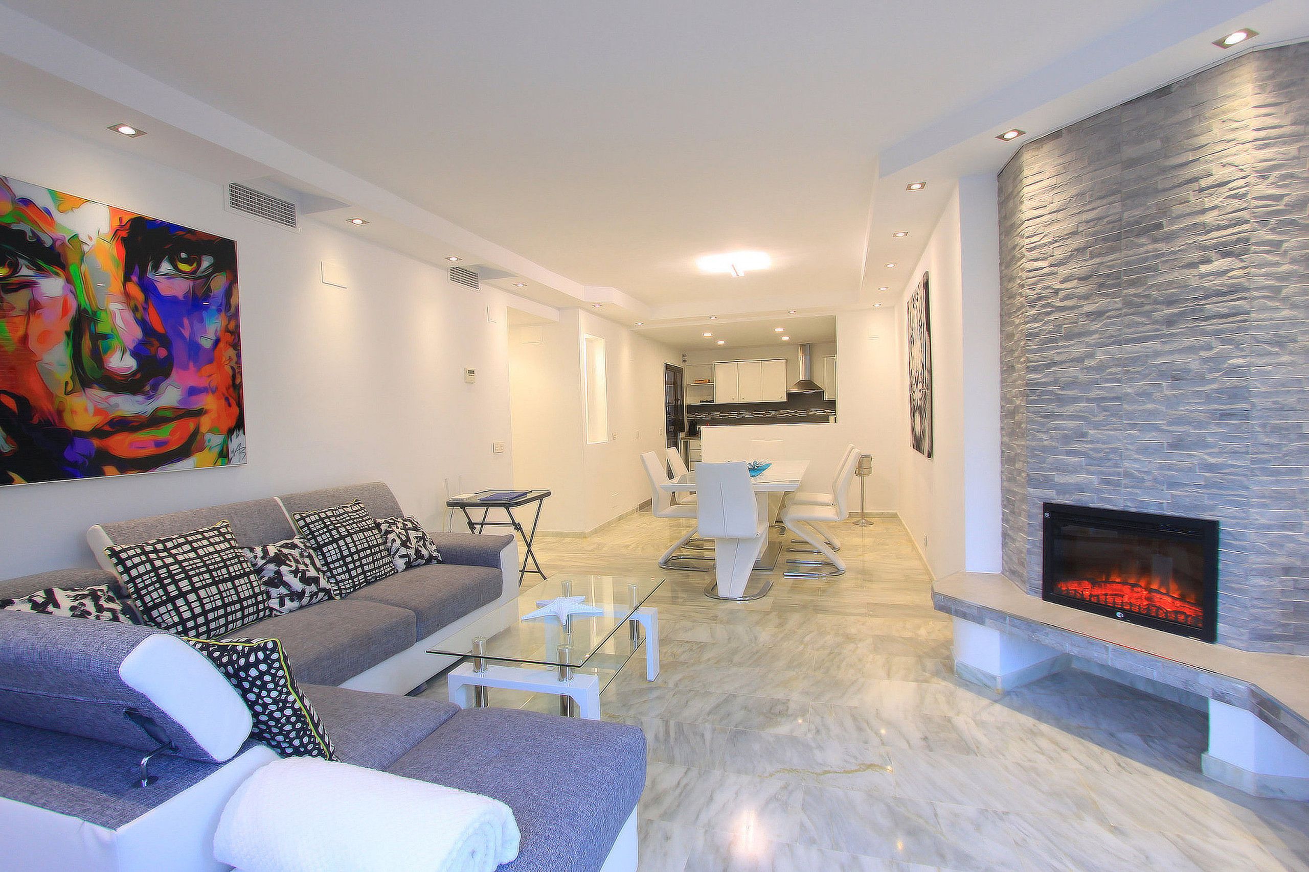 A modern living room with a sofa, coffee table, and fireplace.