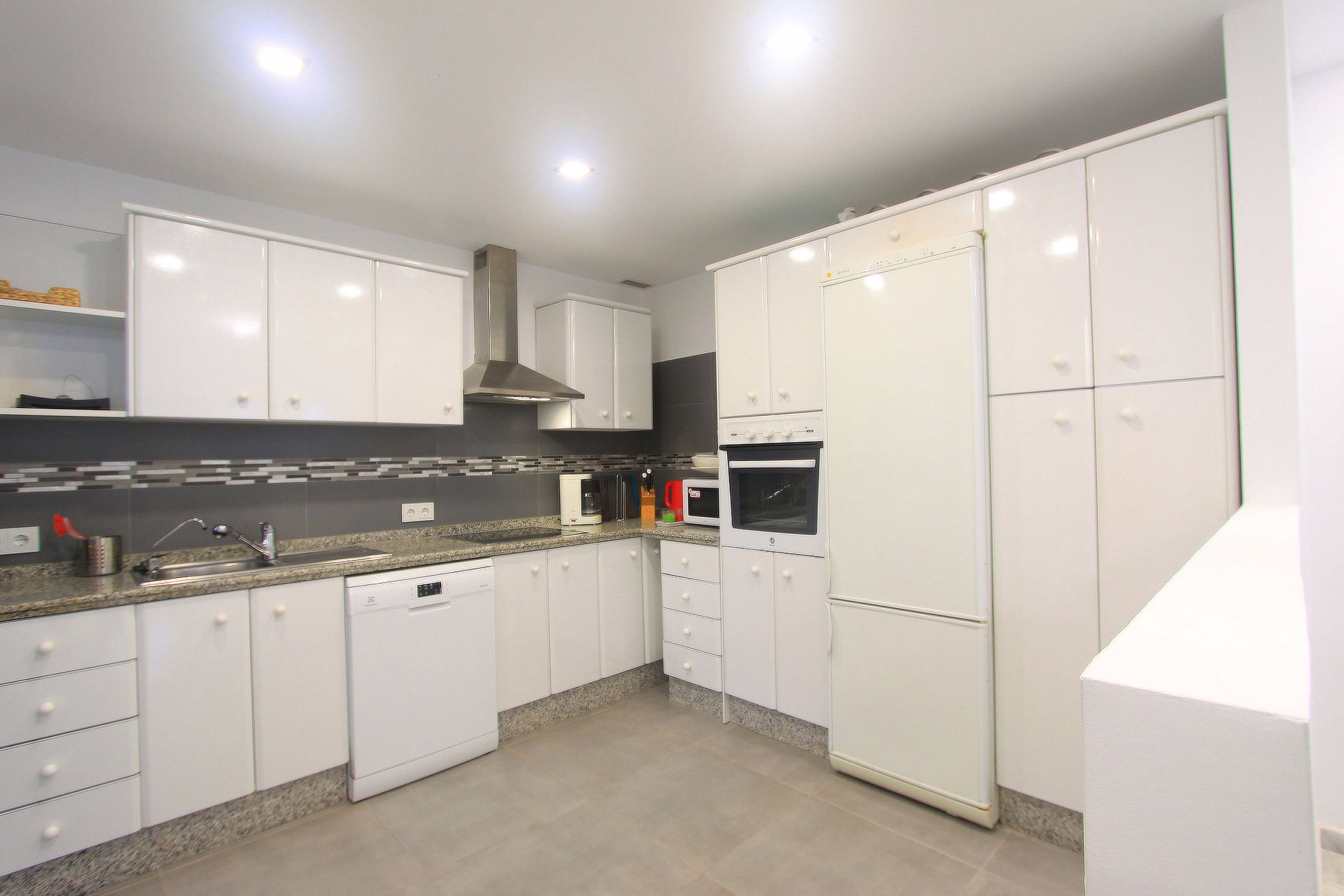 A modern kitchen with white cabinets, a dishwasher, a microwave, and a built-in oven.