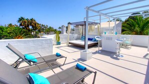 Una terraza en la azotea con sillones de descanso, una zona de estar pequeña y una estructura de pérgola.