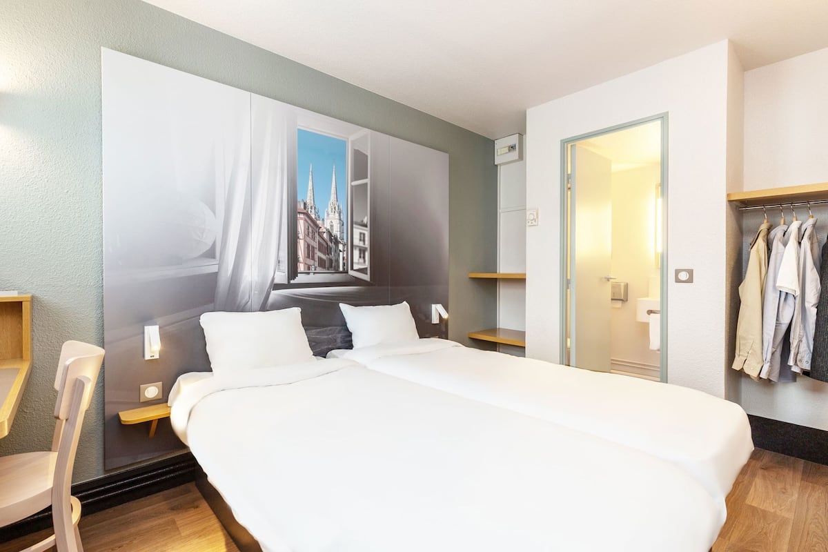 Een hotelkamer met een groot bed, uitzicht op een stadsbeeld door een raam, een kledingkast en een nachtkastje.