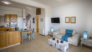 A spacious living area with a kitchen, a sofa, a coffee table, and a TV mounted on the wall. - Beachfront Villa Meneou 5 (Larnaca)