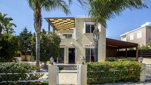 A two-story building with a checkered roof, a covered entrance, and a gated driveway. - Ayia Napa Tropical Beach Villa (Ayia Napa)