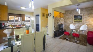 A modern kitchen with a dining area, a living room with a fireplace, and a staircase leading to another level. - Ayia Napa Tropical Beach Villa (Ayia Napa)