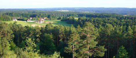 A rural landscape with scattered houses, dense forests, and rolling hills.
