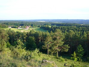 Un paysage rural parsemé de maisons, de forêts denses et de collines ondulantes.