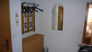 Een kamer met een houten garderobe, een kapstok met ophangers, een spiegel en een telefoon op een standaard.