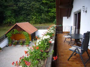 Eine Terrasse mit einer Holzkonstruktion, Sitzgelegenheiten im Freien und Kübelpflanzen.