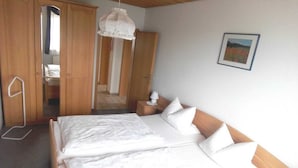 A bedroom with a bed, wooden wardrobe, and a hanging light fixture.