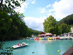 Ein See mit Booten, einem Steg und einem Gebäude mit rotem Dach.