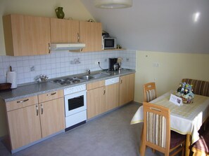 A kitchen with wooden cabinets, a microwave, a stove, and a dining area with a table and chairs.