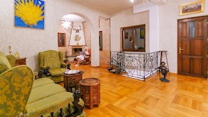 A spacious living room with a fireplace, green upholstered furniture, and a wooden floor. - Casa Natalia (Sinaia)