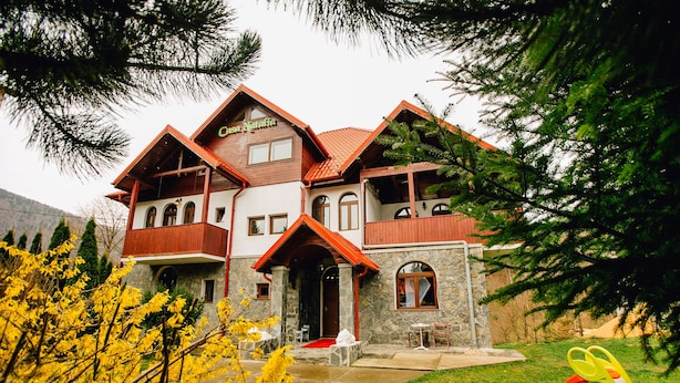 A two-story house with a stone facade, wooden balconies, and a red-tiled roof. - Casa Natalia (Sinaia)