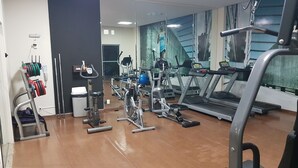 A gym with various exercise equipment including treadmills, stationary bikes, and weight machines. - Charming Furnished Studio Flat (Goiania)