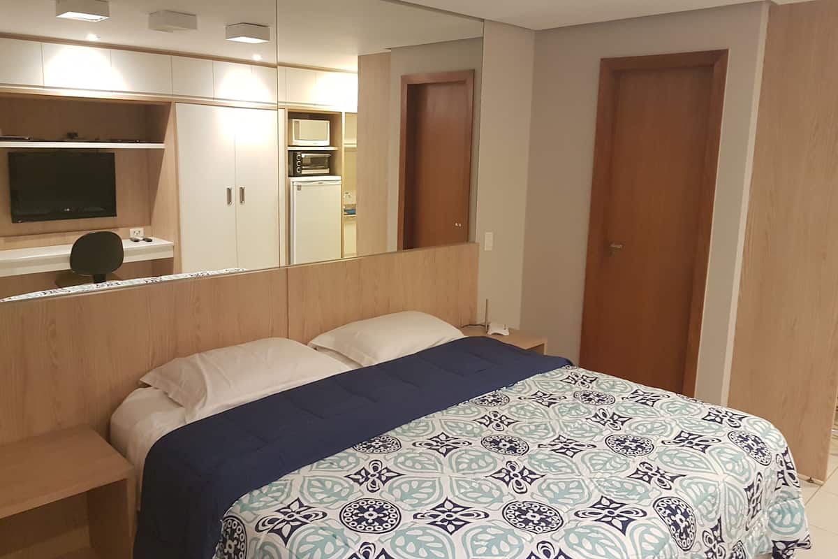 A bedroom with a bed, a desk, a television, and a wardrobe.
