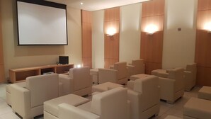 A modern home theater with plush seating, a large screen, and wall-mounted speakers. - Charming Furnished Studio Flat (Goiania)