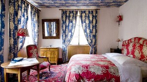 Una camera da letto tradizionale con un letto, una cassettiera in legno, una sedia, un tavolo e uno specchio.