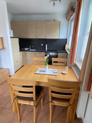 Una cocina compacta con armarios de madera, una encimera negra y una mesa de comedor con sillas.
