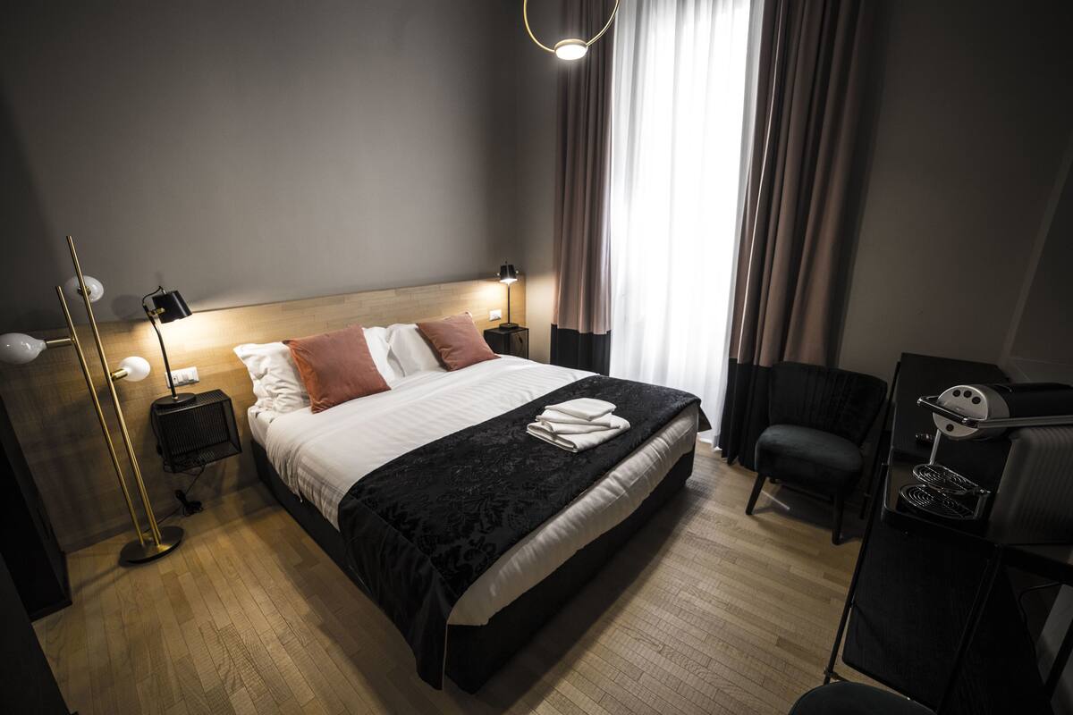 Ein modernes Hotelzimmer mit einem großen Bett, Nachttischlampen, einem Schreibtisch und einem Sessel.