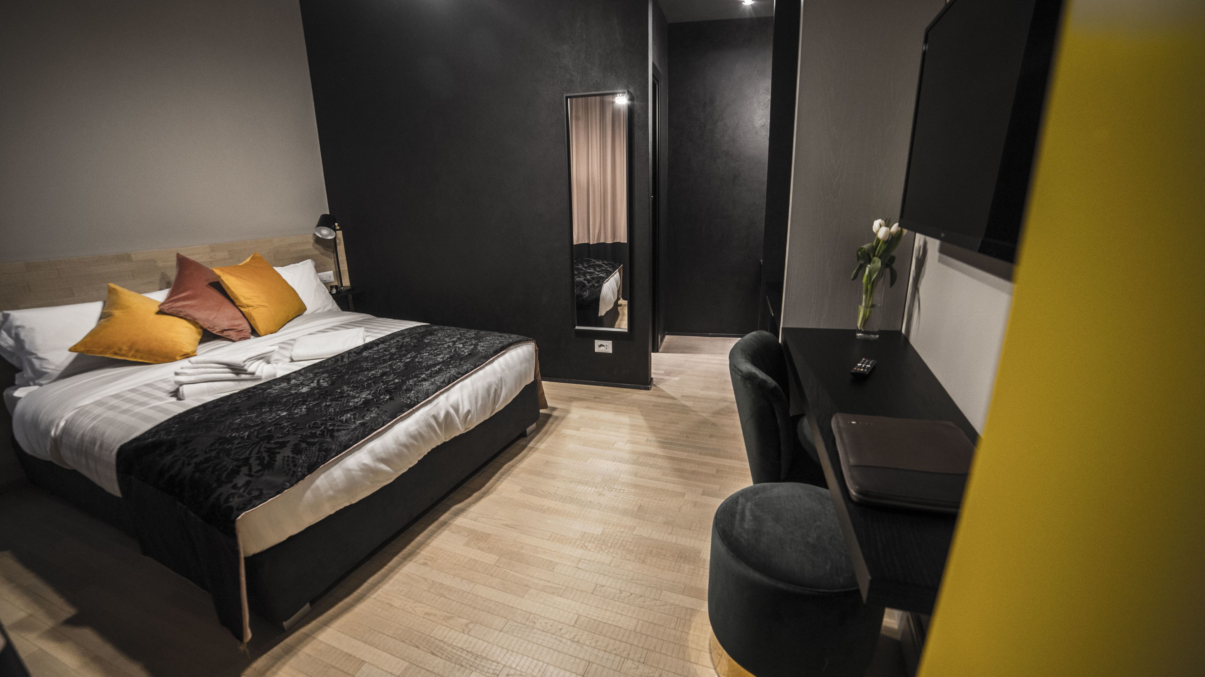 A modern hotel room with a large bed, a desk, and a mirror.