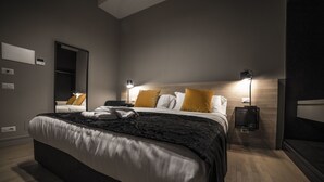 Un dormitorio moderno con una cama grande, dos lámparas de noche, un espejo y una mesita de noche.