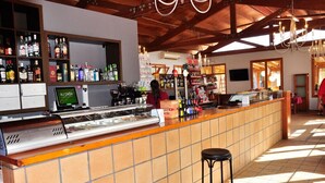 A bar area with a tiled counter, a cash register, and a variety of bottles on shelves. - Camping La Estanca (Alcaniz)