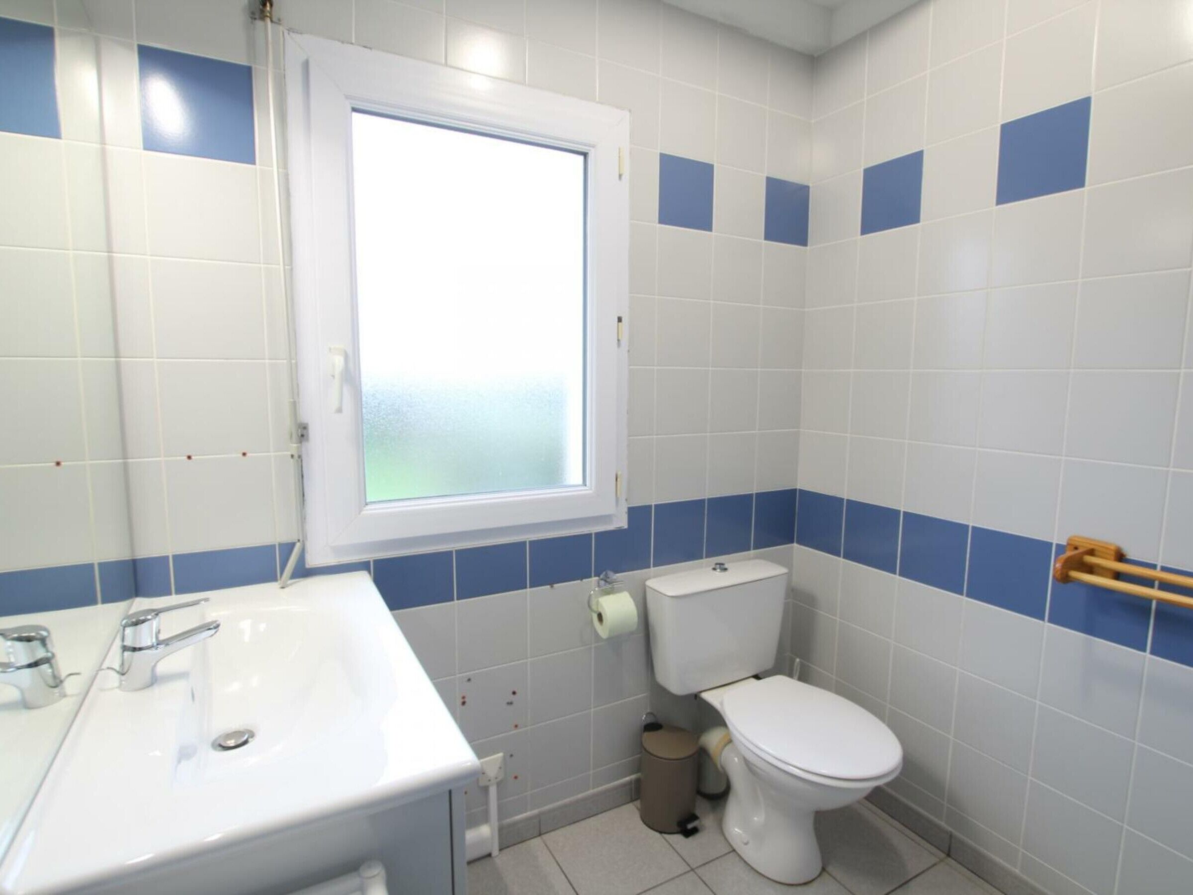 A bathroom with a white sink, a toilet, and a window.