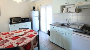 A compact kitchen with a dining table, microwave, refrigerator, sink, and a dishwasher. - Cottage near the sea with parking and pets allowed (Siouville-Hague)
