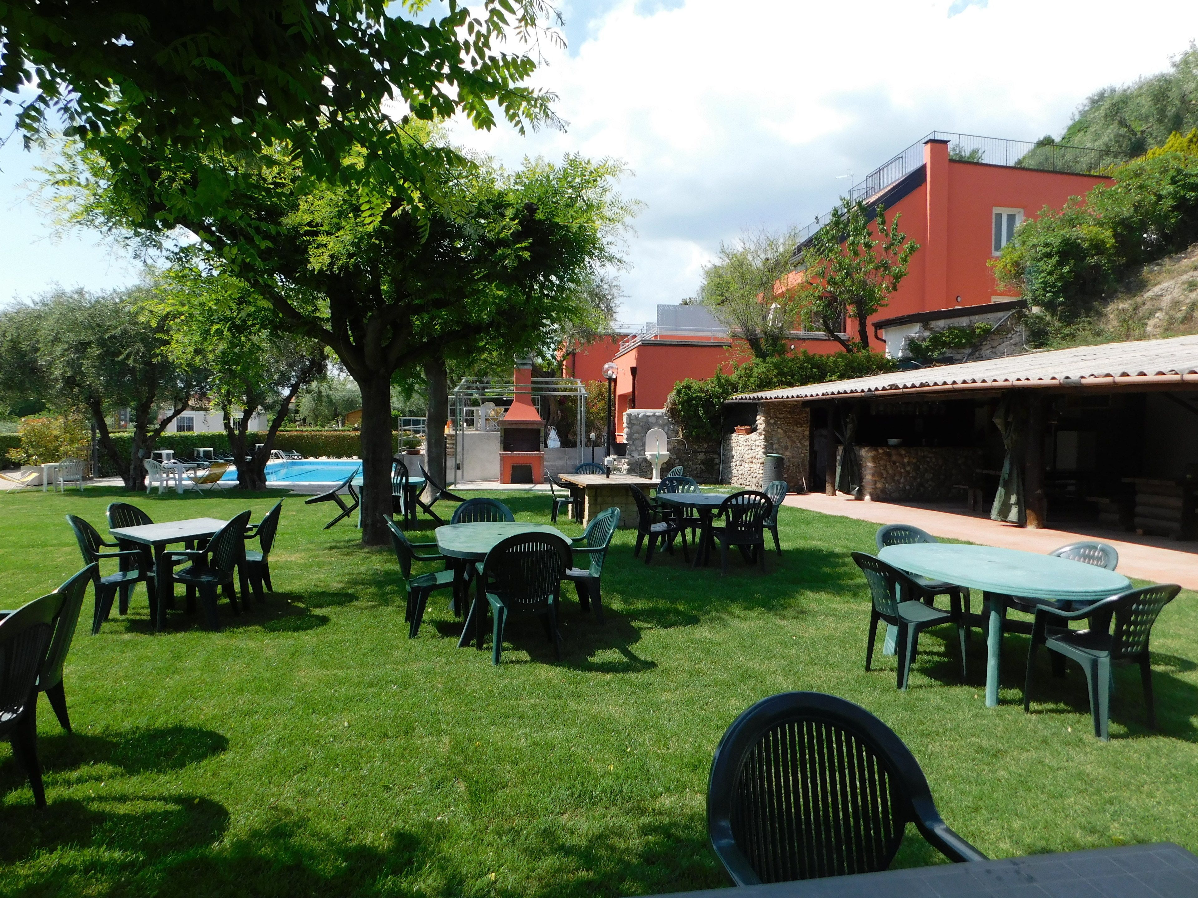 An outdoor patio area with tables and chairs, a barbecue grill, and a swimming pool.