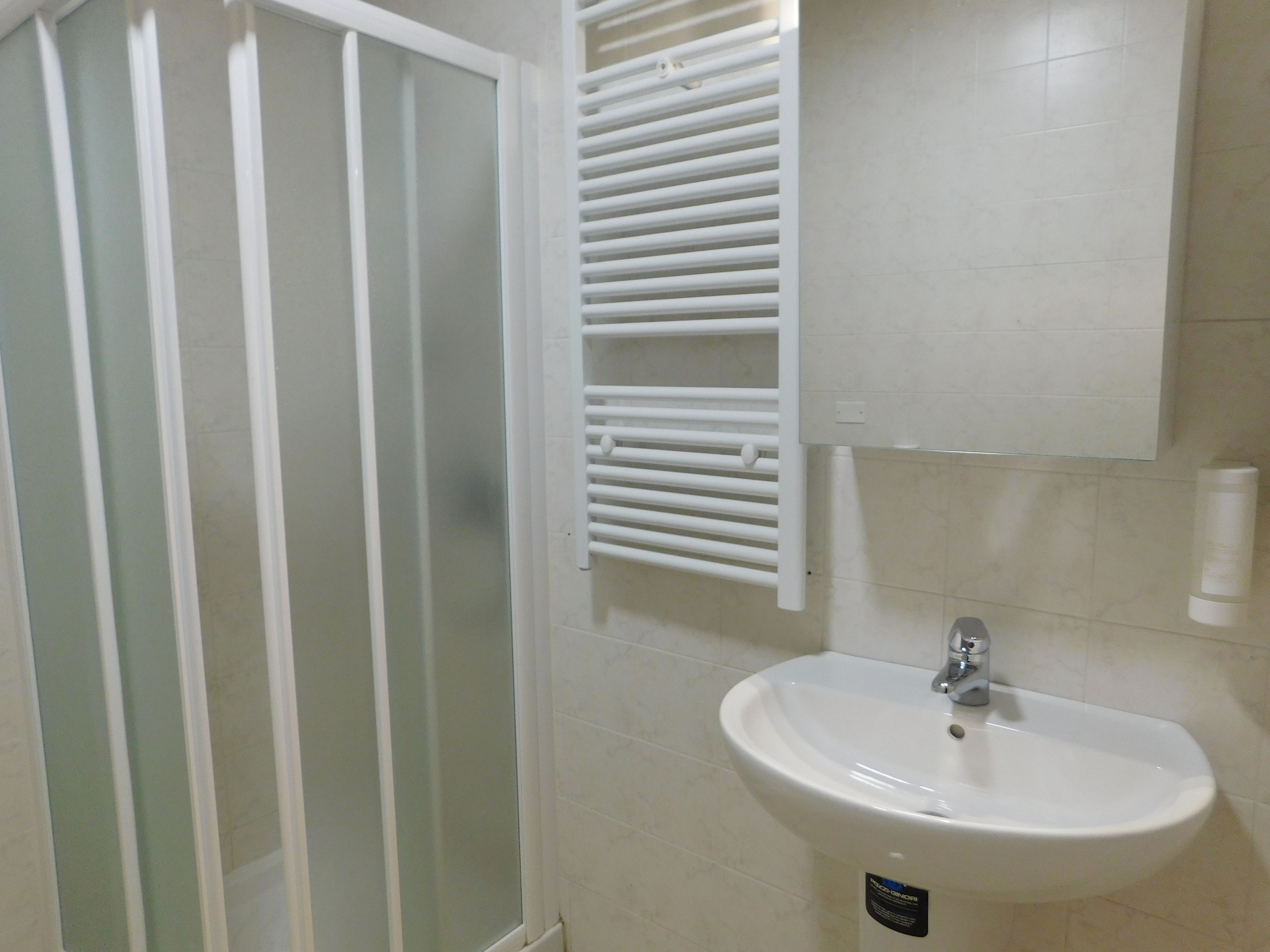A bathroom with a white sink, a mirror, and a glass shower enclosure.