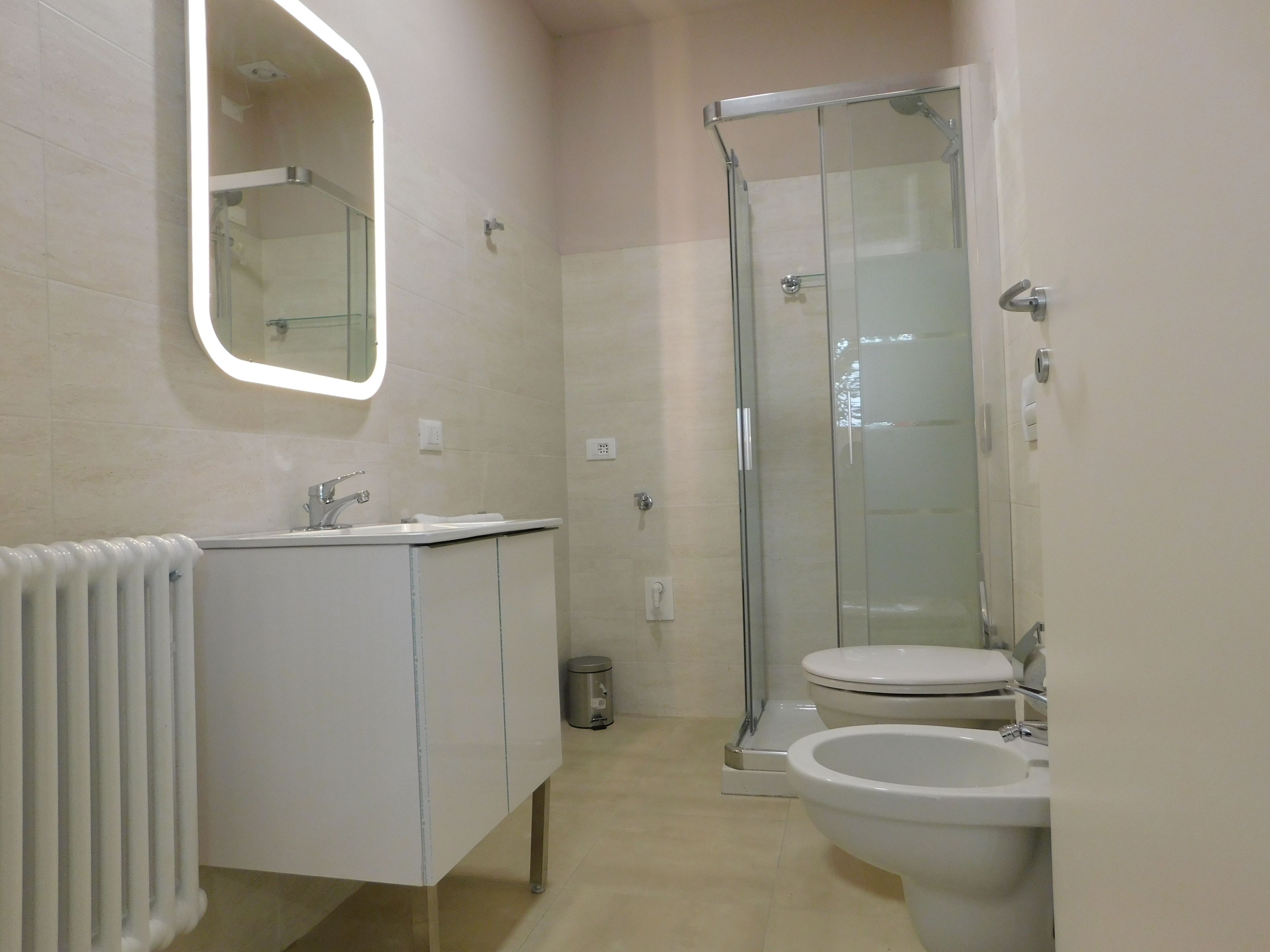 A modern bathroom with a glass shower enclosure, a white sink, and a toilet.