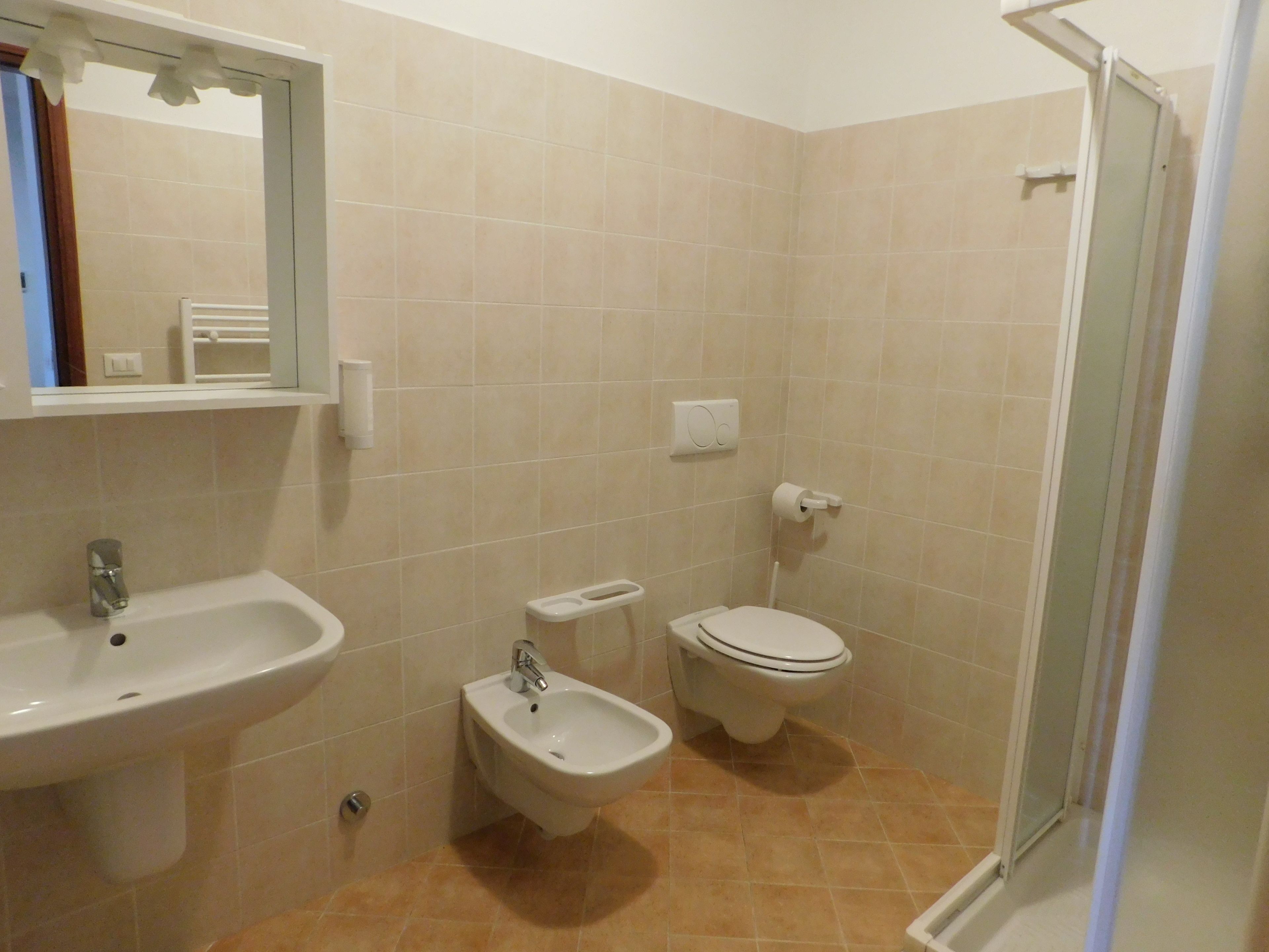 A bathroom with a sink, bidet, toilet, and a shower area.