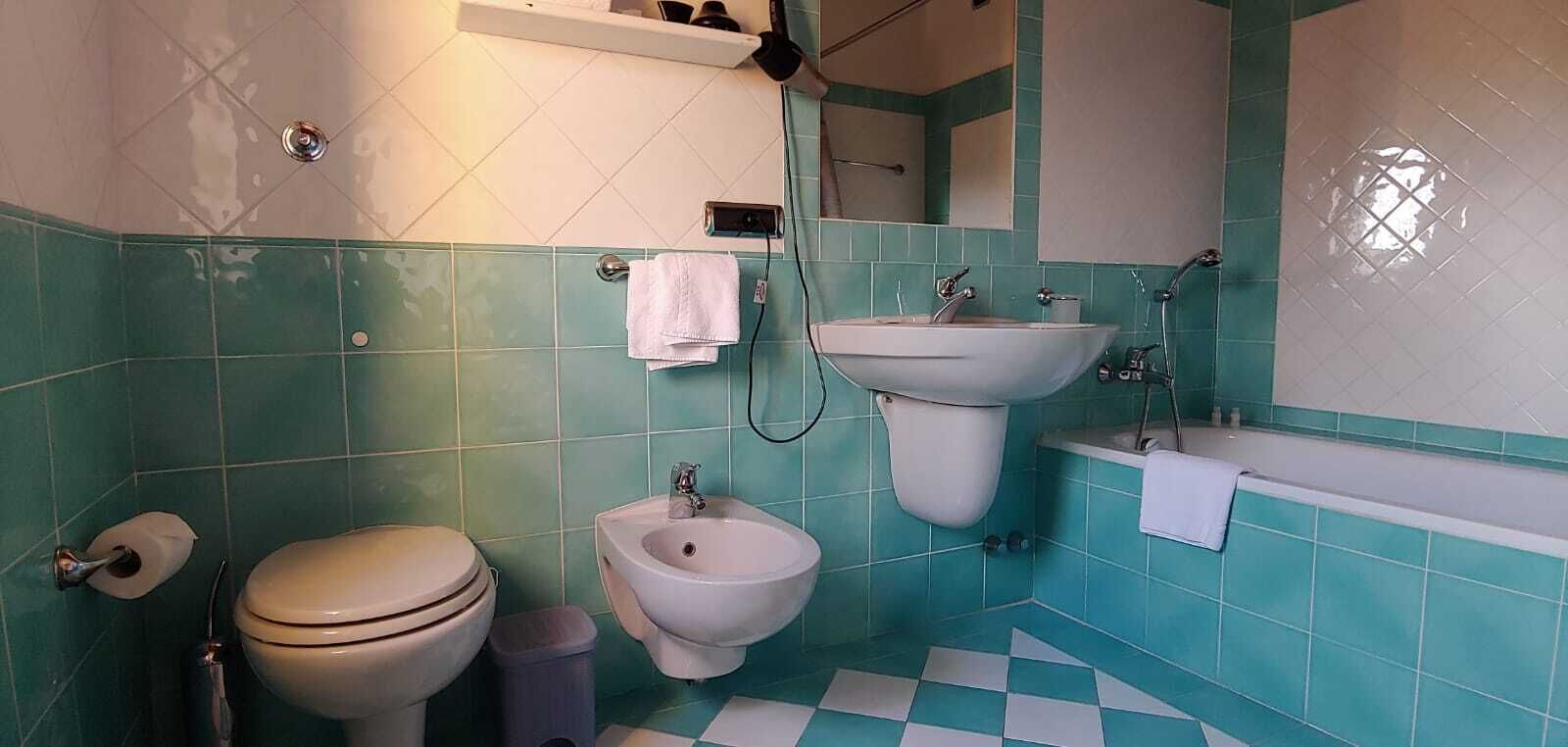 A bathroom with a toilet, bidet, sink, and bathtub.