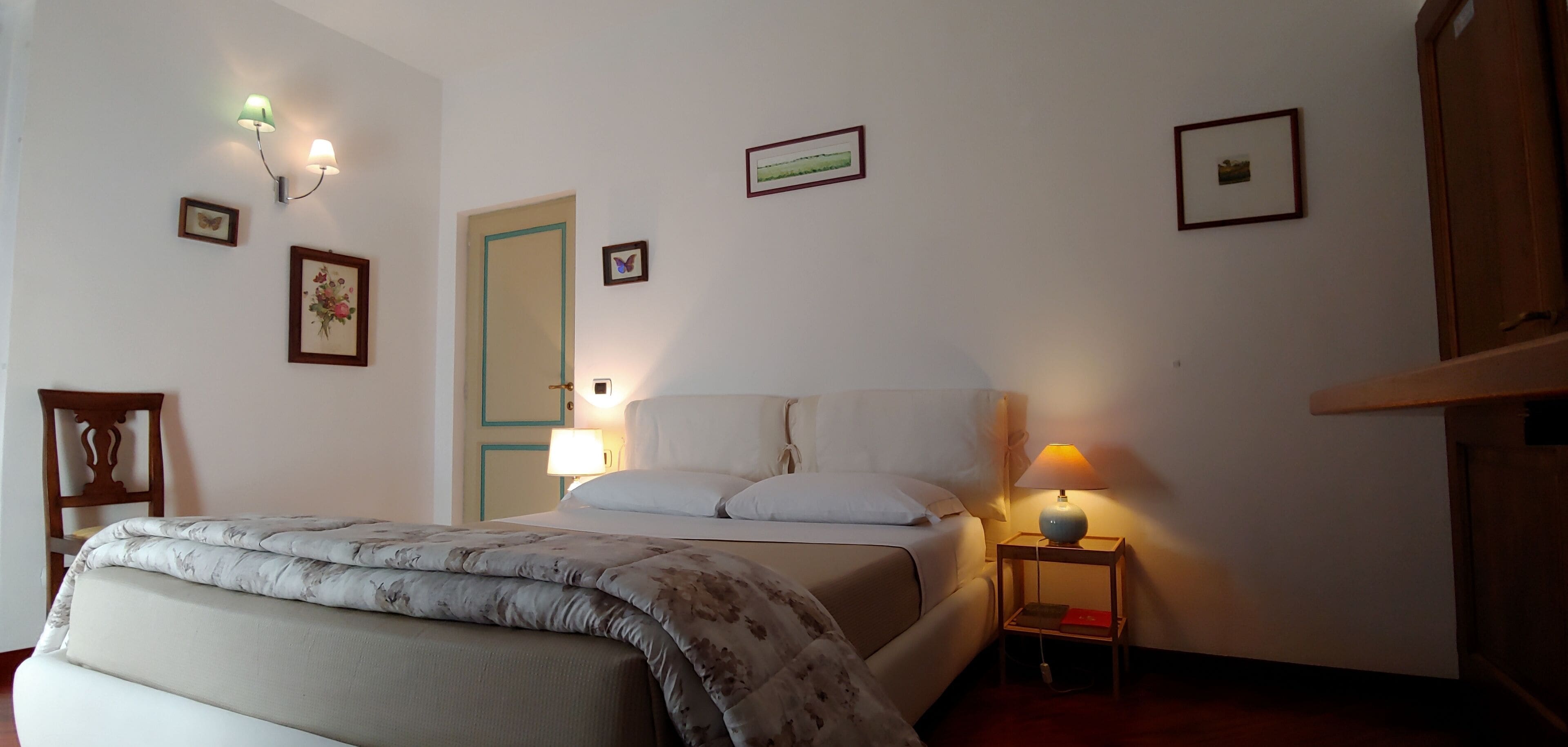 Un dormitorio con cama, lámparas de noche, mesita de noche y lámparas de pared.