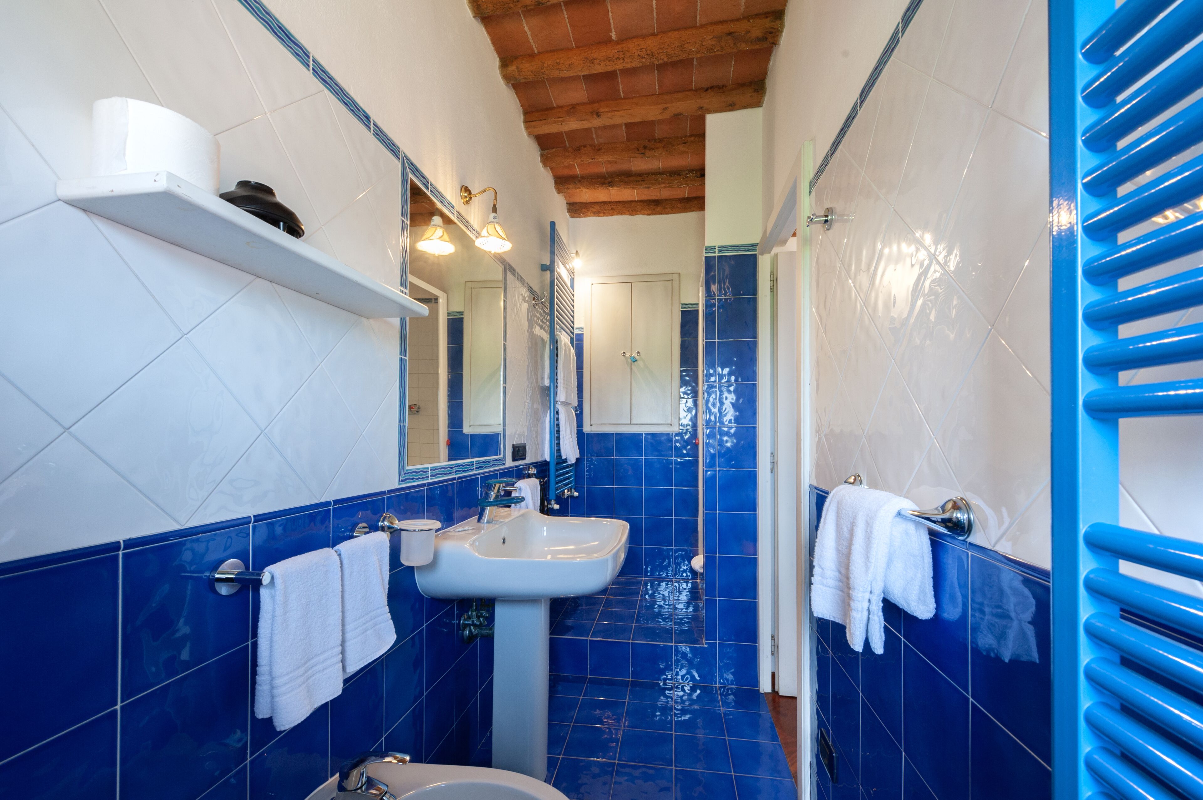 A bathroom with blue tiles, a white sink, a mirror, and a towel rack.