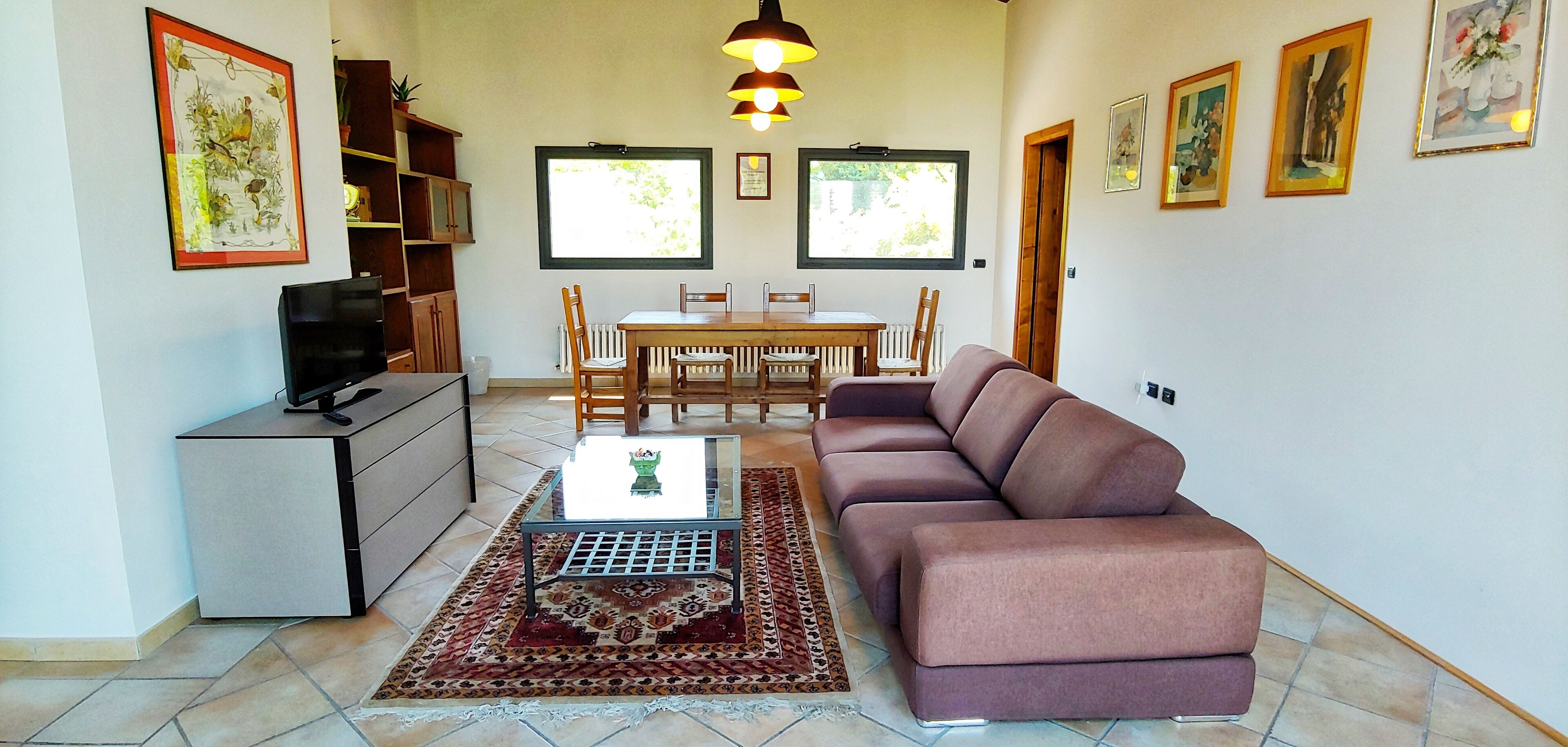 Un soggiorno con divano, TV, tavolino da caffè e zona pranzo con sedie e tavolo.
