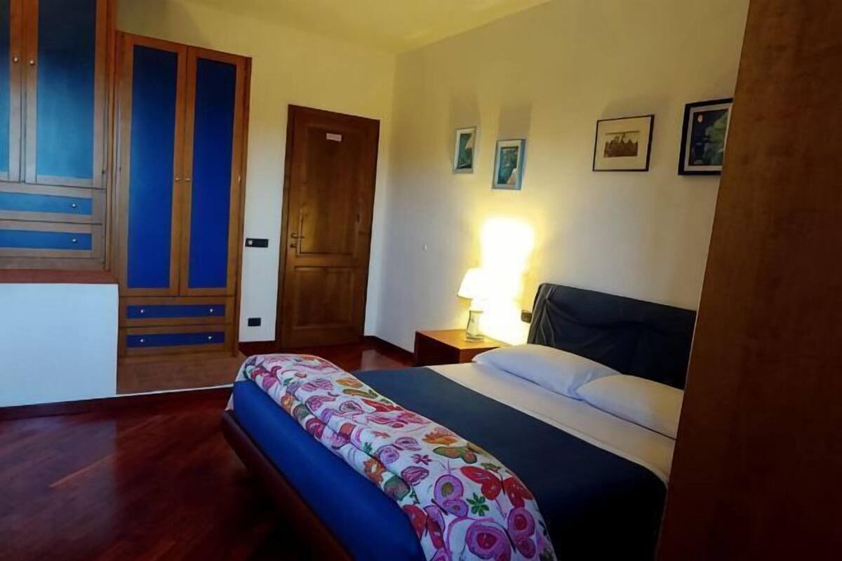 A bedroom with a bed, a nightstand, a wooden wardrobe, and a door.