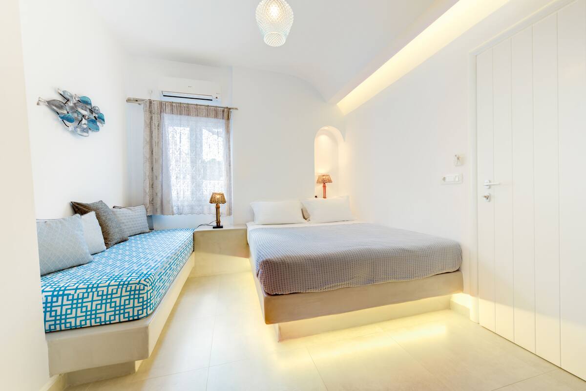 Un dormitorio moderno con cama, mesitas de noche y una zona de estar.