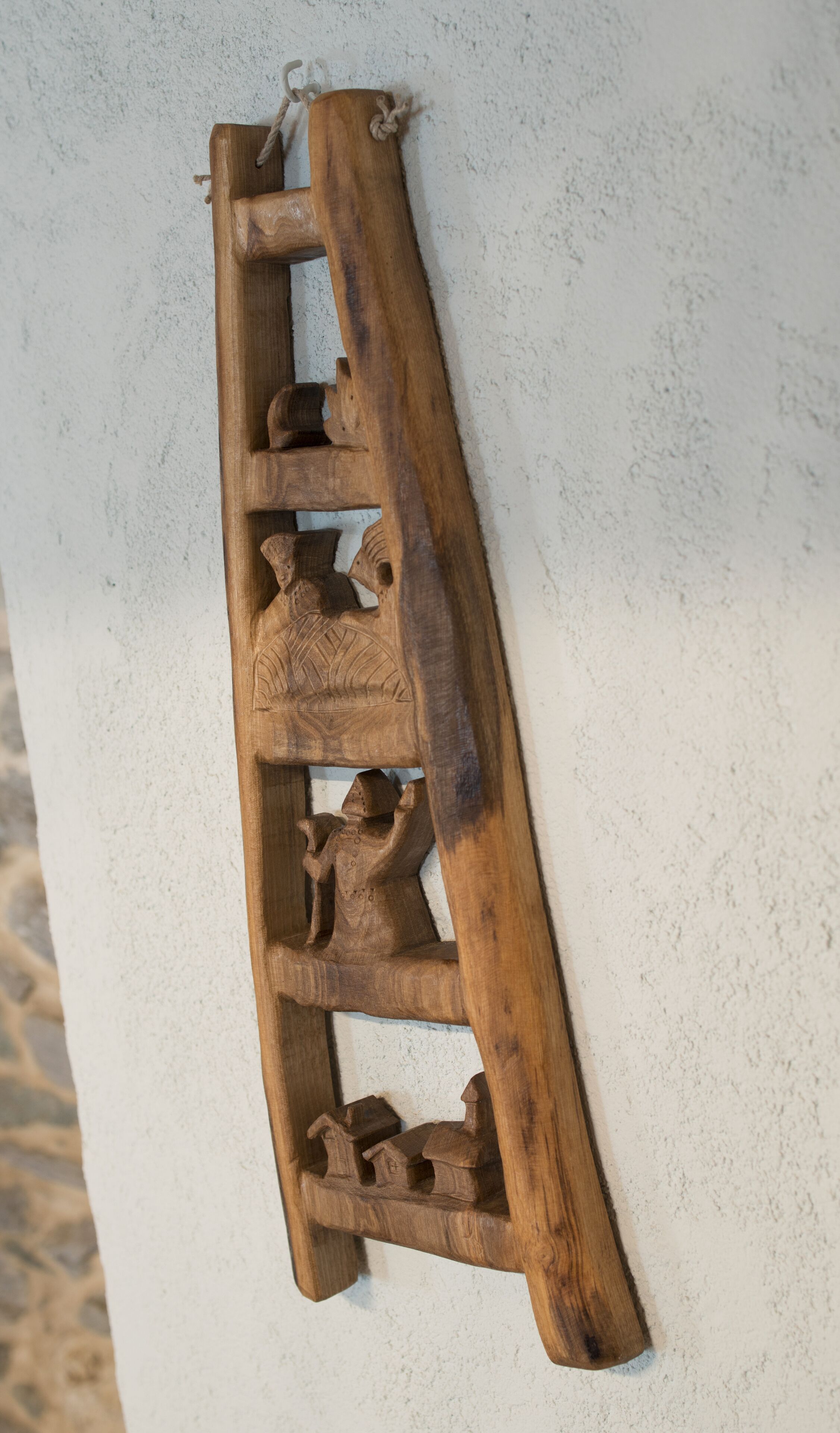 Eine hölzerne Leiter mit geschnitzten Figuren an jedem Treppchen.
