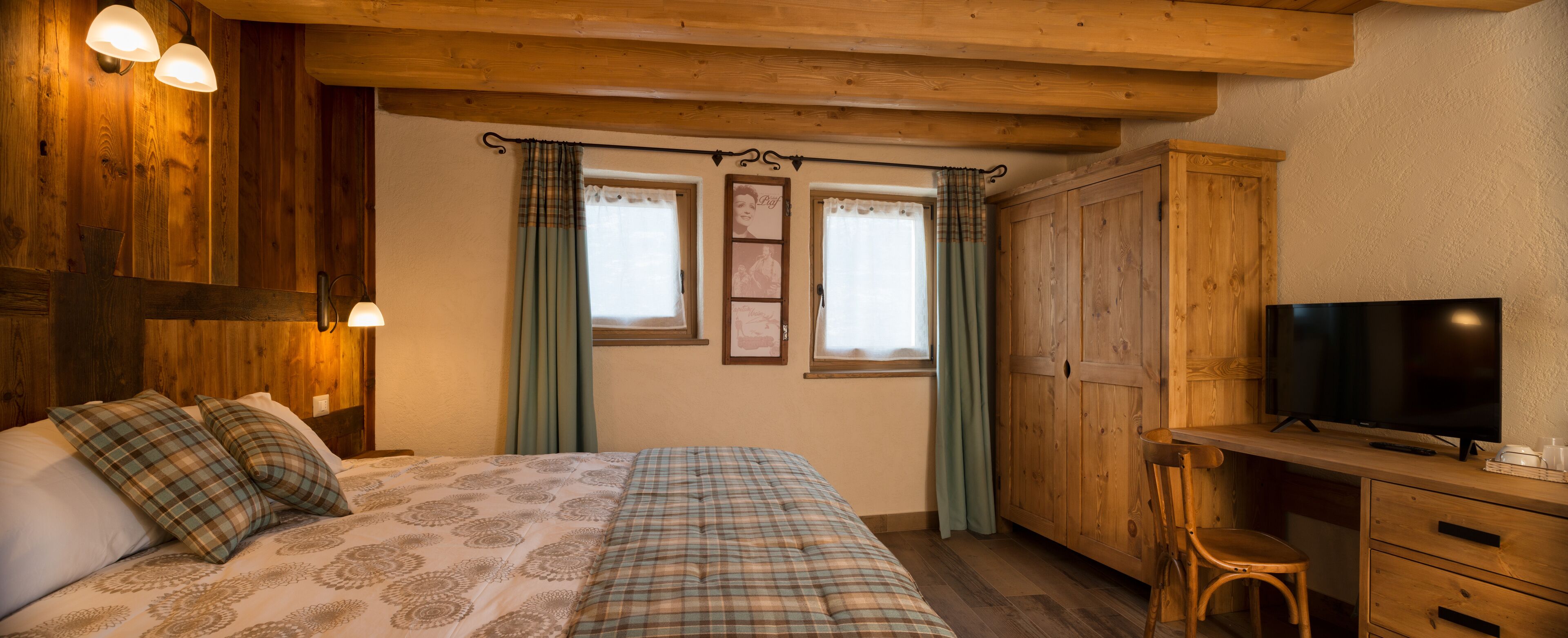 Un dormitorio acogedor con una cama, un escritorio, un televisor y paredes de madera.